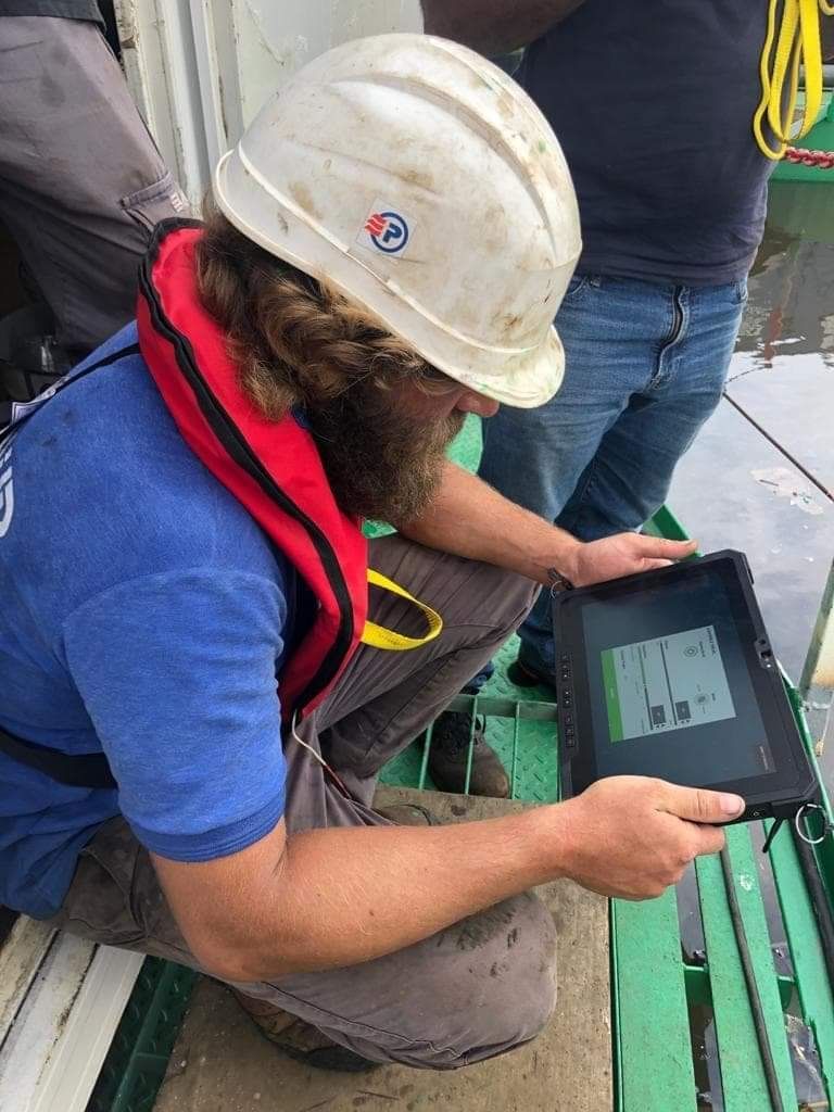 Opérateur pilotant la barge depuis une tablette durcie