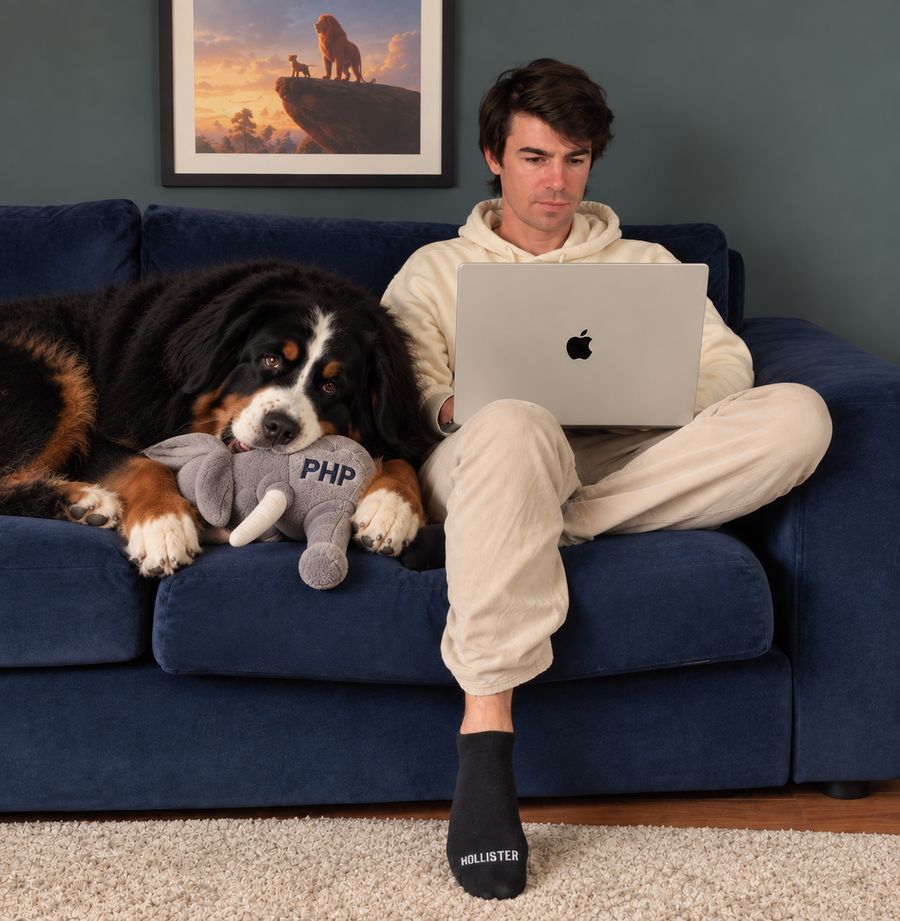 Fabien sur son canapé avec son ordinateur, un gros chien couché à côté avec une peluche PHP